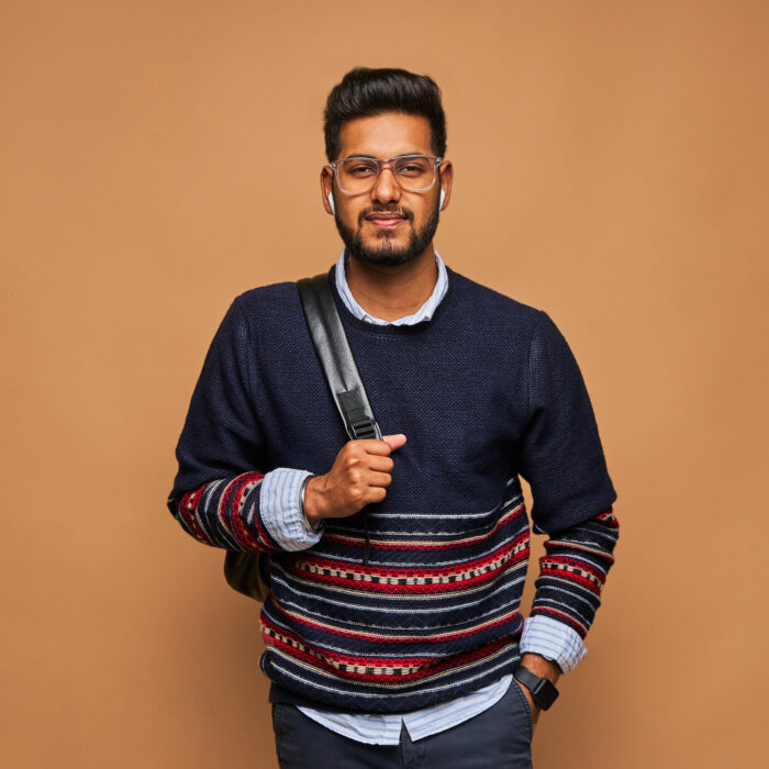 Young bearded hindu student with backpack on pastel background.